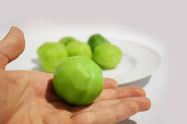 Une main tenant un kiwi vert à moitié frais ou une groseille à maquereau tropicale nutritive à faible teneur en calories, isolée sur un fond de kiwi tranché — Photo