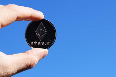 Gümüş Ethereum sikke mavi gökyüzü arka plan üzerinde tutan el