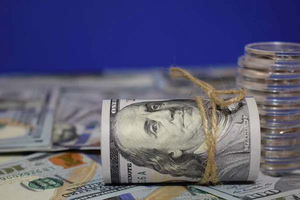 Roll, amerikai dollár, a háttérben a szétszórt száz dollár számlák — Stock Fotó
