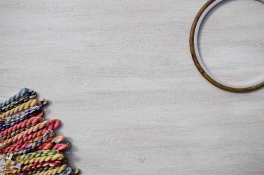 Yaratıcı sanat için nakış çemberleri ve hafif bir arka plan üzerinde nakış için örgülü diş ipi iplikleri. Boş metin alanı.
