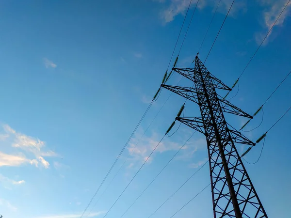 Yüksek voltajlı elektrik hatları mavi gökyüzü bulutlu destekler. Elektrik Sanayi. — Stok fotoğraf