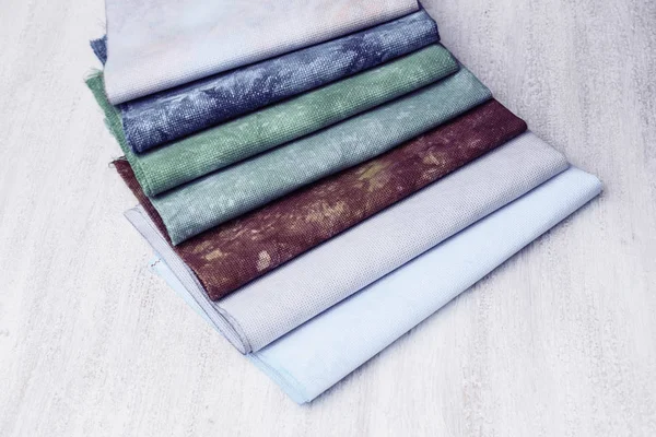 Cortes de tecido multicoloridos, sobreposição dobrada. Tecidos para costura em um fundo branco . — Fotografia de Stock