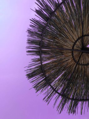 Mor gökyüzüne karşı samandan yapılmış plaj şemsiyesi. Aşağıdan görüntüle