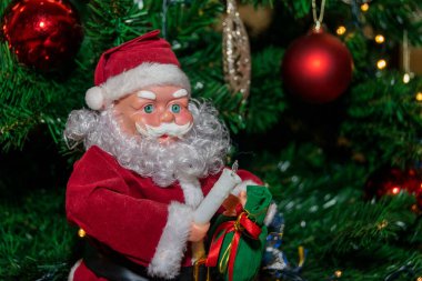 Noel Baba Noel ağacının yanında oturuyor.