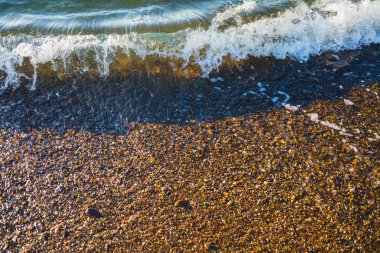 Dalgalar deniz kıyısında çakıl taşları