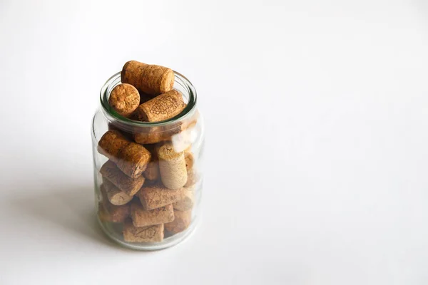 Wine corks lie in a glass jar on a white background. The bank is located on the left side