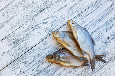 Üç kurutulmuş balık çipura üzerinde ahşap masa lambası yalan.