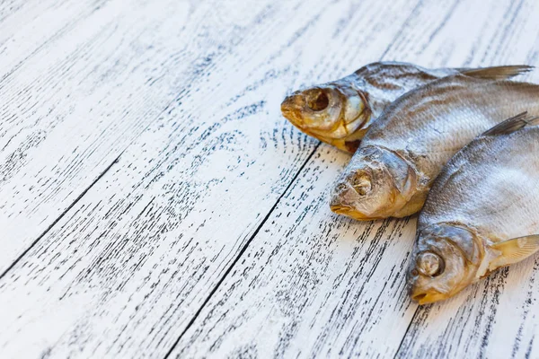 Tres doradas de pescado secas yacen sobre una mesa de madera clara . —  Fotos de Stock