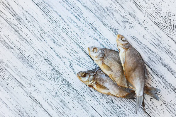 Tres doradas de pescado secas yacen sobre una mesa de madera clara . —  Fotos de Stock