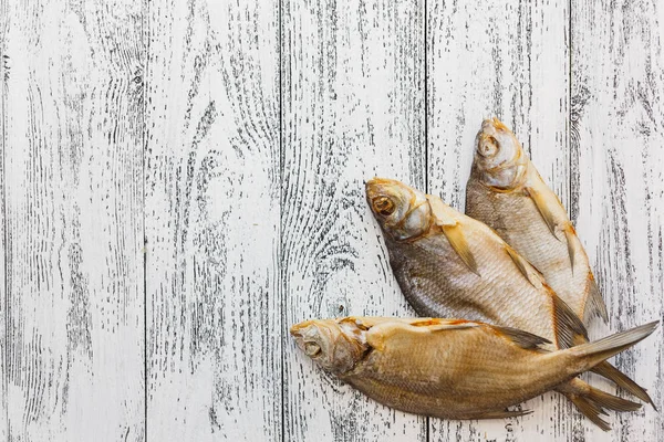 Tres doradas de pescado secas yacen sobre una mesa de madera clara . —  Fotos de Stock