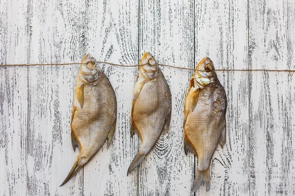 Tre orate di pesce essiccate si trovano su un tavolo di legno leggero — Foto Stock