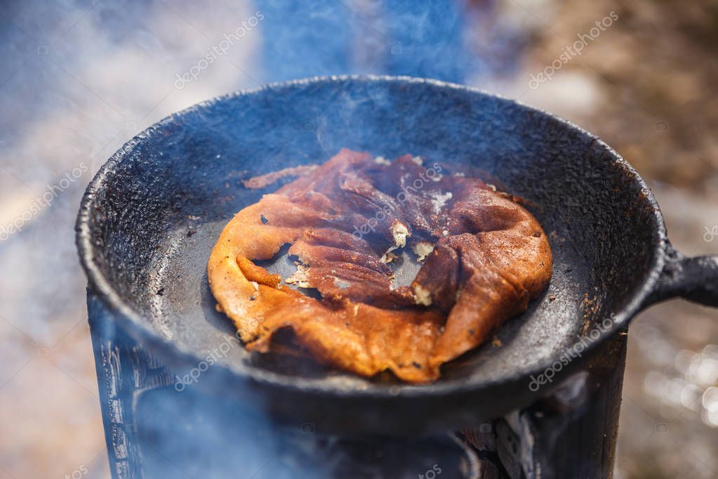 Un panqueque quemado en una sartén. Cocinar al aire libre en el fuego 2022