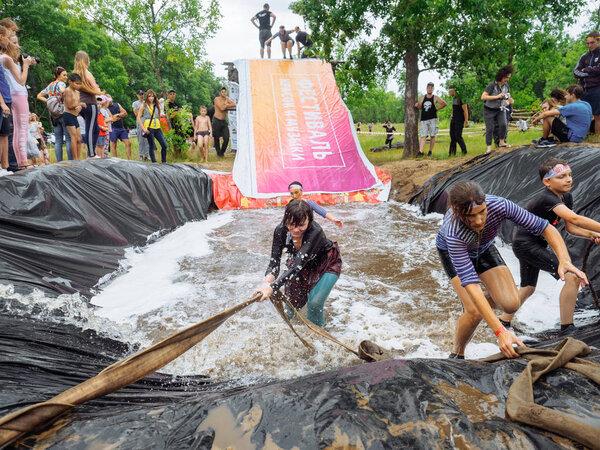 RUSSIA, Bryansk - June 30, 2019: Obstacle Race. Athletes in suits jump into a pit of water.
