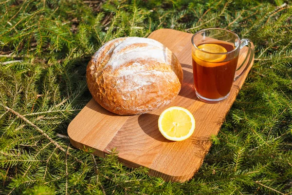 Färsk vitt bröd på en skärbräda och rött te med citron. — Stockfoto