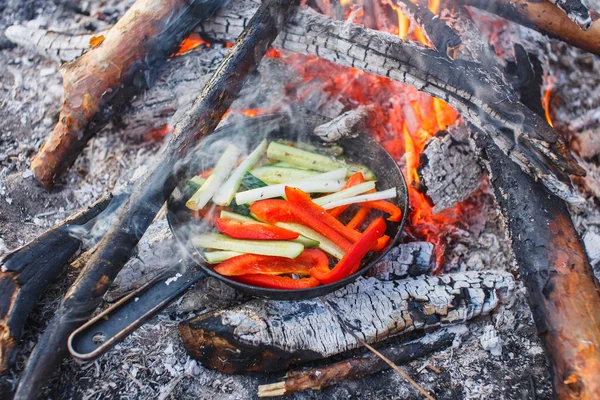 Cooking dishes from red bell peppers and cucumbers in a pan on a fire — Stock Photo, Image