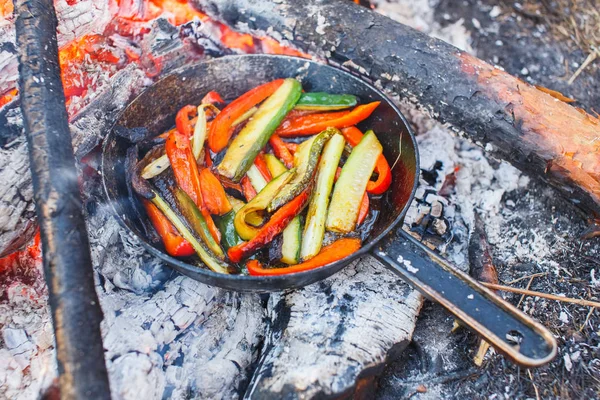 Un plat de poivrons rouges et de concombres dans une casserole sur un feu — Photo