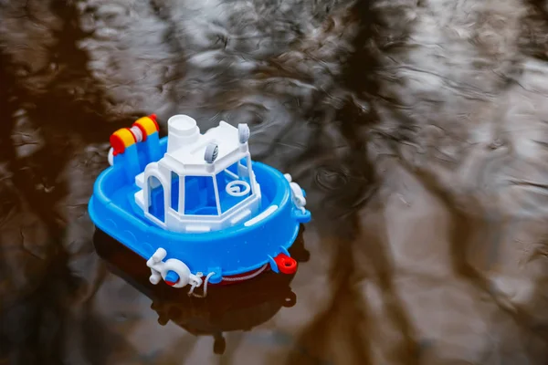 Un pequeño barco de juguete navega a lo largo de un río del bosque al atardecer — Foto de Stock