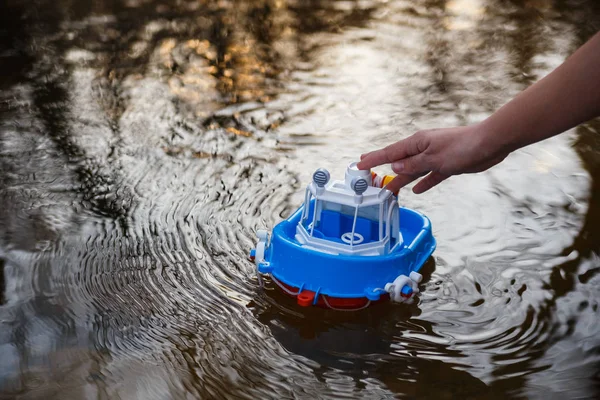 A girl plays in a river with a small toy ship — Stock Photo, Image