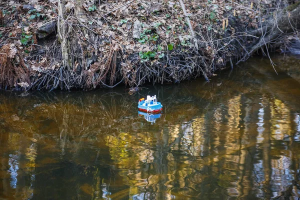 Toy ship sailing in the river at sunset