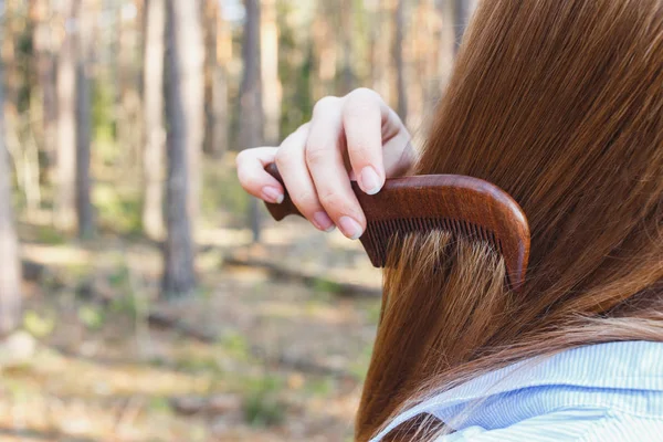 Dívka pročesující vlasy dřevěným hřebenem v lese — Stock fotografie
