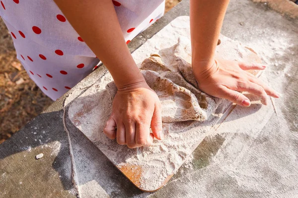 Flickan i ett vitt förkläde förbereder degen på en skärbräda — Stockfoto