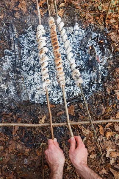 The cook prepares the dough on skewers on the fire in the spring forest — Stock Photo, Image