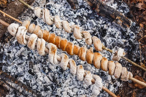Making dough on skewers on a fire in the spring forest — Stock Photo, Image