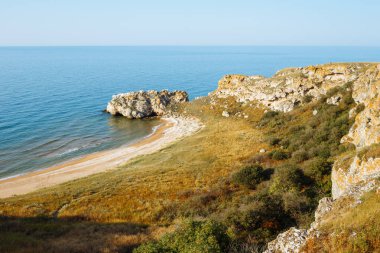 Gün batımında kayalıkların içinde vahşi deniz Körfezi ve kumlu plaj