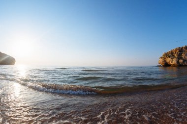 Gün batımında vahşi bir koyda dalgalar ile deniz