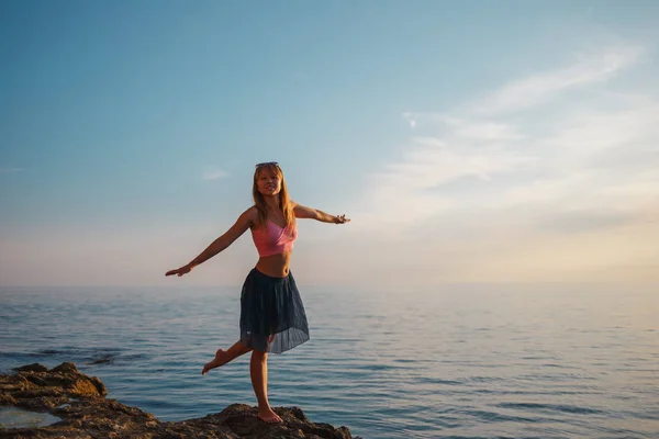 Chica en las rocas en el mar al atardecer — Foto de Stock