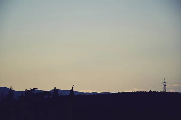 Crimea karanlık tuşlu minimalist siluet günbatımı yataydan dağlar, ağaçlar ve güç hat desteği