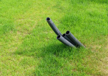 Yeşil çim üzerinde yerden metro araçları için plastik borular çıkıntı. Ekoloji kavramı
