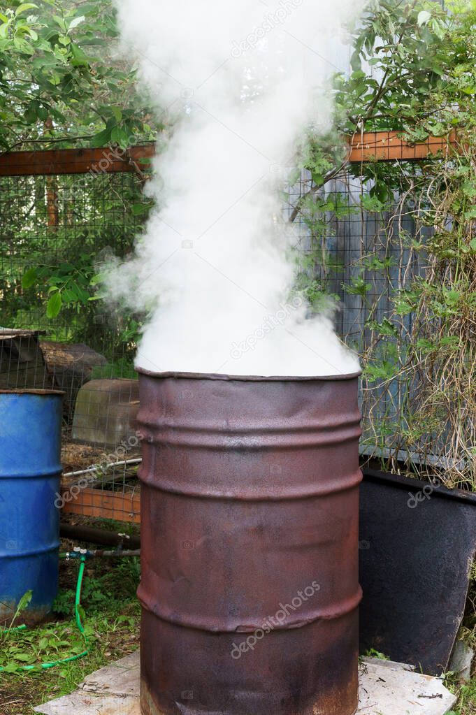 Garbage incineration in rusty metal barrel with release of large amount of smoke. Harm to environment and human health
