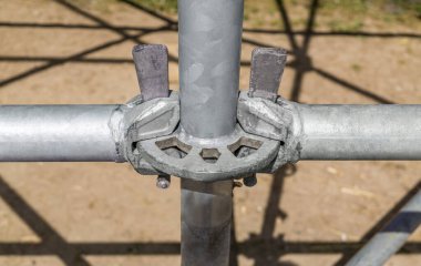 Elementleri geçici metal yapısına bağlamak için oruç tutmak. İnşaat alanı. Güneşli bir gün. Küçük alan derinliği