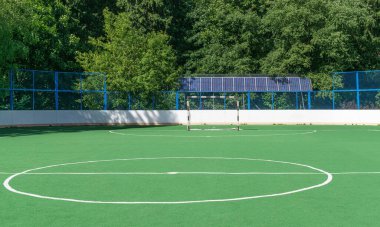 Sports ground near forest for mini soccer or hockey. Solar panels installed behind fence. Copy space clipart