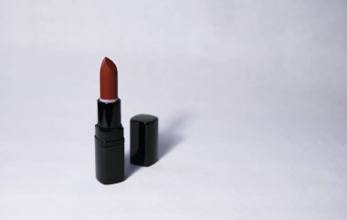 Havuç renginde ruj beyaz bir arka plan üzerinde merkezi bir siyah kapaklı dikey olarak açık duruyor