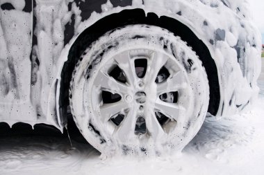 Lavabodaki deterjan köpüğünde gri bir arabanın tekerleği.