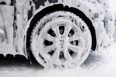 Lavabodaki deterjan köpüğünde gri bir arabanın tekerleği.