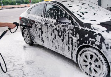 Köpük tabancasıyla lavaboda yıkanmış gri bir araba.