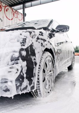 Köpükte gri bir araba var. Deterjandan. Lavaboda duruyor.