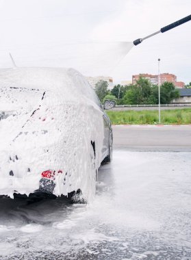 Araba yan tarafta köpüklü ve araba yıkamadaki deterjandan köpükler çıkıyor.