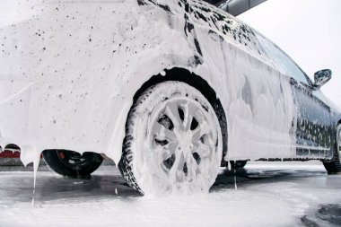 Araba yan tarafta köpüklü ve araba yıkamadaki deterjandan köpükler çıkıyor.