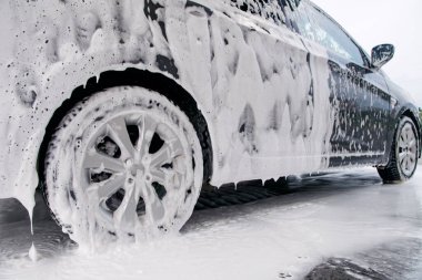 Araba yan tarafta köpüklü ve araba yıkamadaki deterjandan köpükler çıkıyor.