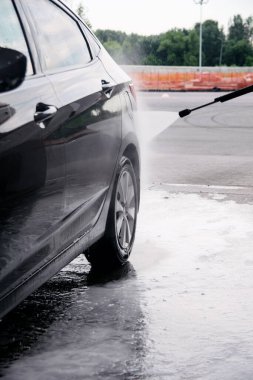 Oto yıkama ile, gri bir arabanın deterjanını suyla yıka.