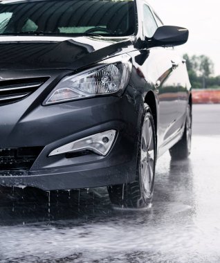 Deterjan gri bir arabanın önünde suyla yıkanmış.