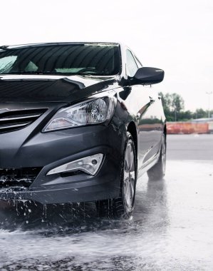 Deterjan gri bir arabanın önünde suyla yıkanmış.