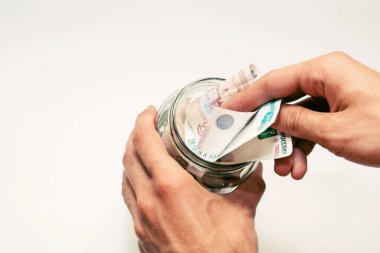 Erkek elleri kağıt para dolu cam bir kavanozu tutuyor.