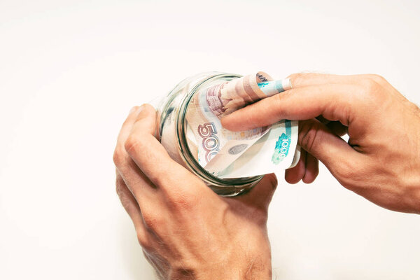 male hands hold a glass jar filled with paper money