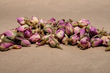 Kurumuş tomurcuklardan ve eflatun çiçeğinin yapraklarından bir demet çay kağıdın arkasında yatıyor.