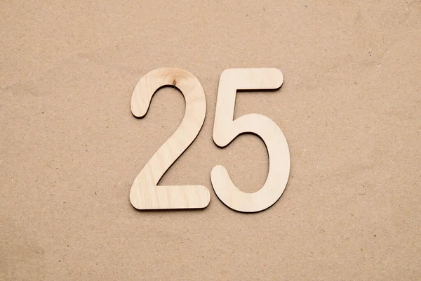 Light wooden numbers 25 lie on craft paper in the center